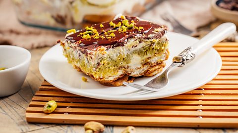 Am image of pistachio tiramisu on a plate with a fork next to it