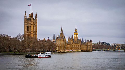 A landscape image shows the Houses of Parliament against a grey sky. In the foreground is the River Thames, with a boat sailing along it. 