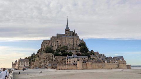 The castle of Mont Saint Michel in Normandy, France. At the top of the hill is the castle structure surrounded by a commune.