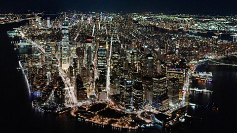 An aerial view of the New York City skyline at night, with all the skyscrapers and building lit up