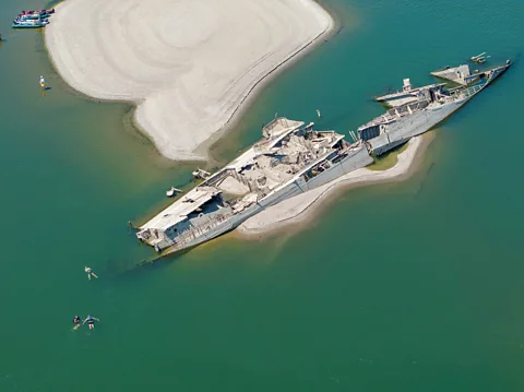 Reuters/ Djordje Kojadinovic A drone view shows people swimming near a sunken WW2 warship in Prahovo, Serbia, (Credit: Reuters/Djordje Kojadinovic)