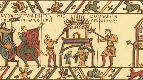 Alamy A woman and child stand fearfully as Norman soldiers casually torch their home (Credit: Alamy)