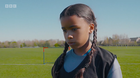 Girl looking slightly disappointed on a football pitch