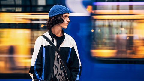 Teenage boy on station platform awaiting train alone