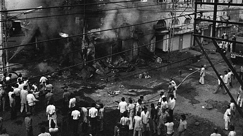 Indian bystanders look on as a building belonging to Sikh merchants burns in Delhi.