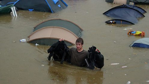 Man wades through floodwater at Glastonbury festival camp site