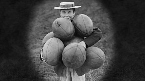 Harrow boy with armful of rugby balls circa 1935