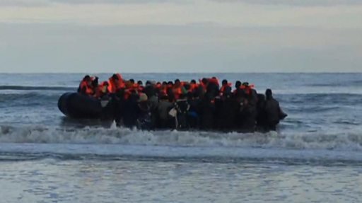I migranti si riuniscono su una piccola imbarcazione a Calais durante una trasmissione della BBC