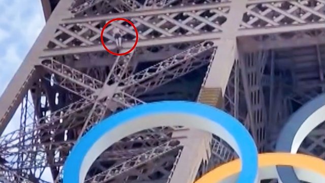 Man seen climbing Eiffel Tower above Olympic rings