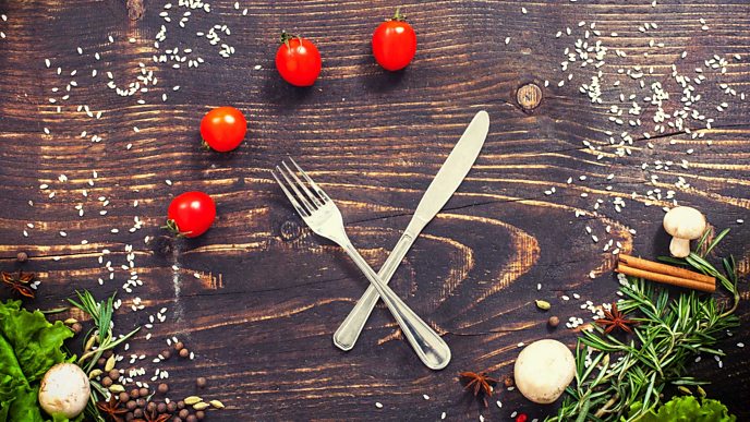 A knife and fork look like a clock with mushrooms and tomatoes being the digits on the clock