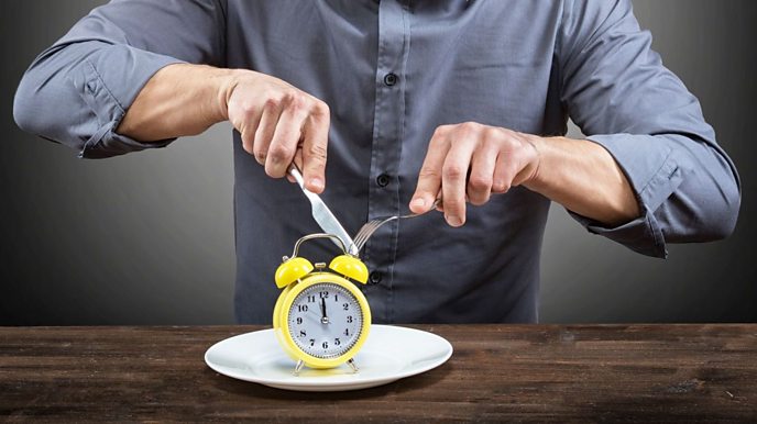 Man sat down to eat with a clock next to him