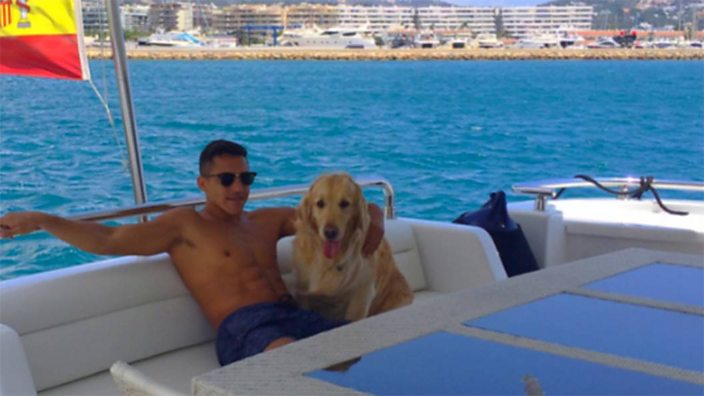 Alexis Sanchez sits on a yacht with his dog