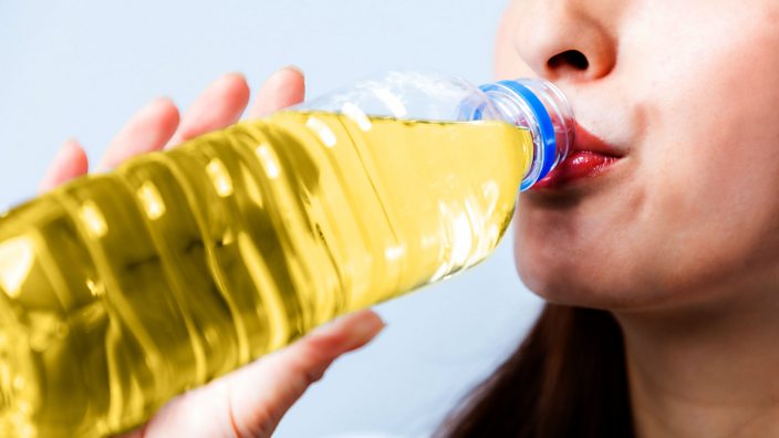 Woman drinking urine out of a plastic water bottle