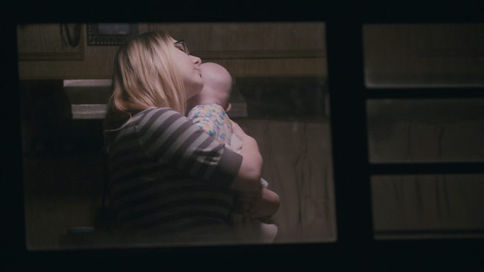 A shot through her trailer window showing Heather holding her baby