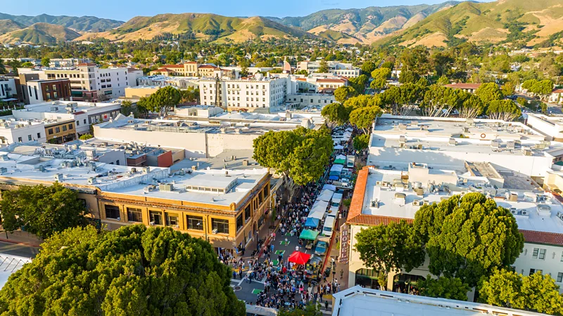 Aerial view of downtown San Luis Obispo with a busy street market, low-rise buildings and surrounding green hills (Credit: Visit San Luis Obispo)