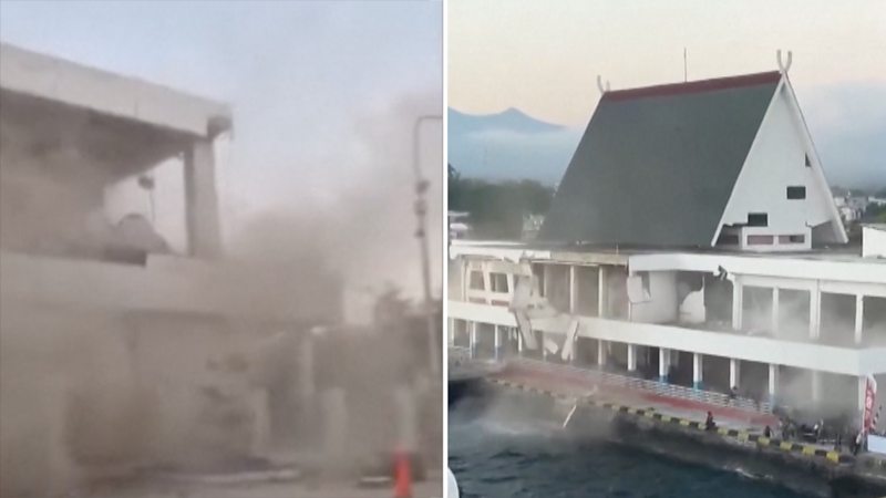 On the left, a concrete building is surrounded by dust. On the right, a building with a peaked roof collapses.