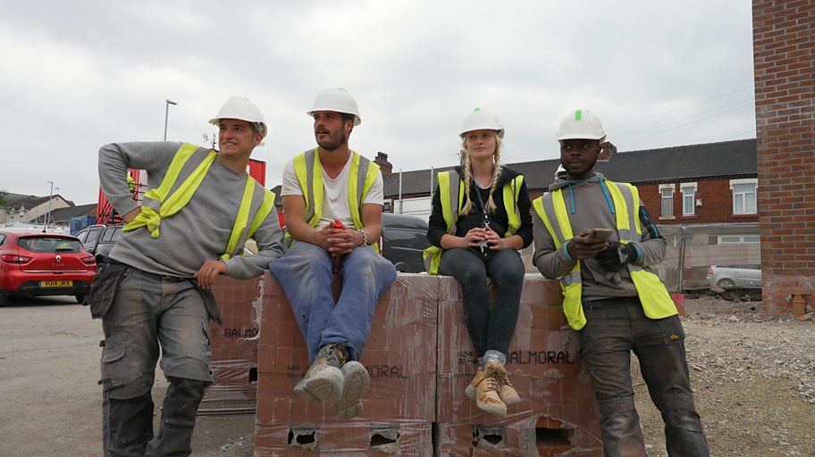 Four bricklayers sit on a stack of bricks