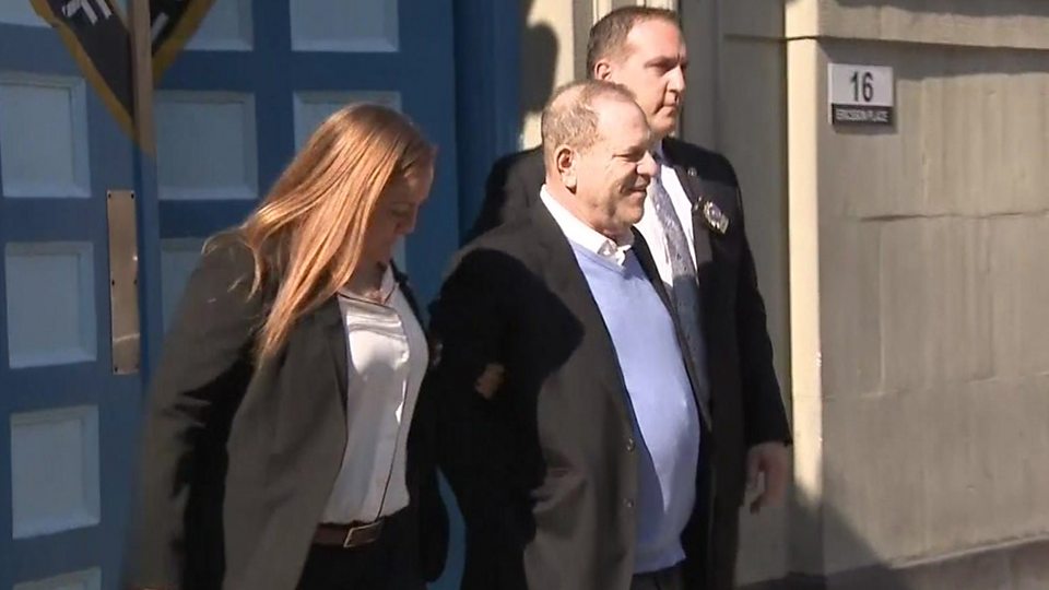 Weinstein smiles as he is led away in handcuffs