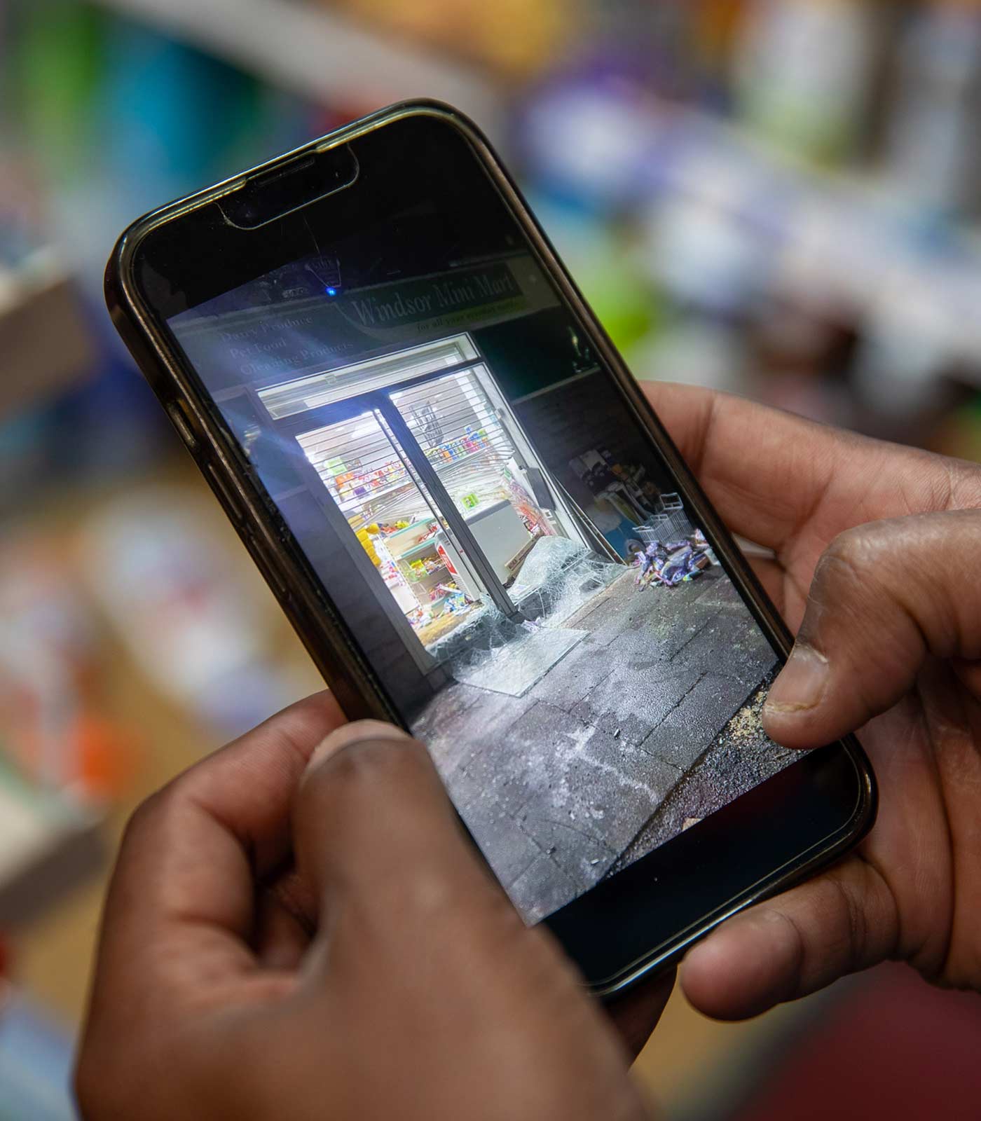 Chanaka Balasuriya watches footage of his shop on his phone