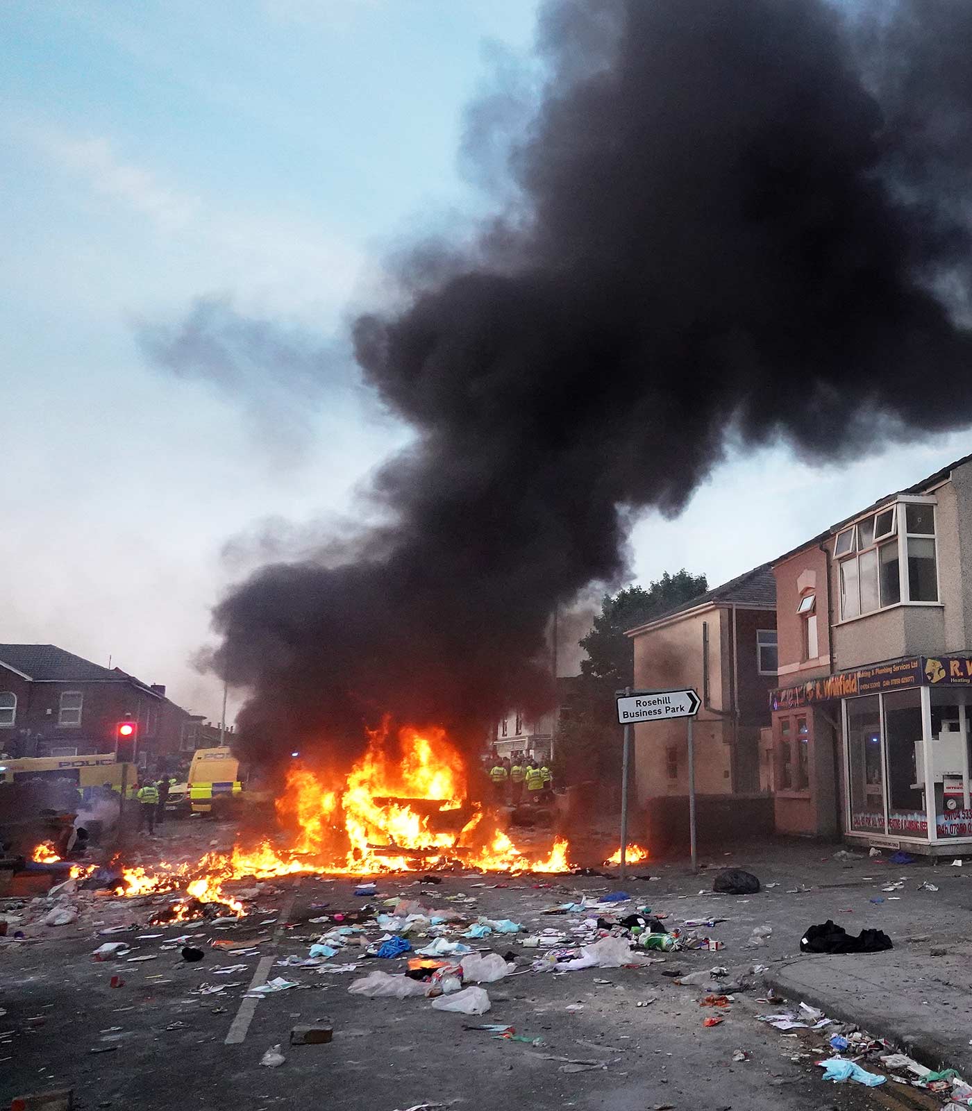 Police hold back rioters near a burning police vehicle in Southport - 30 July 2024