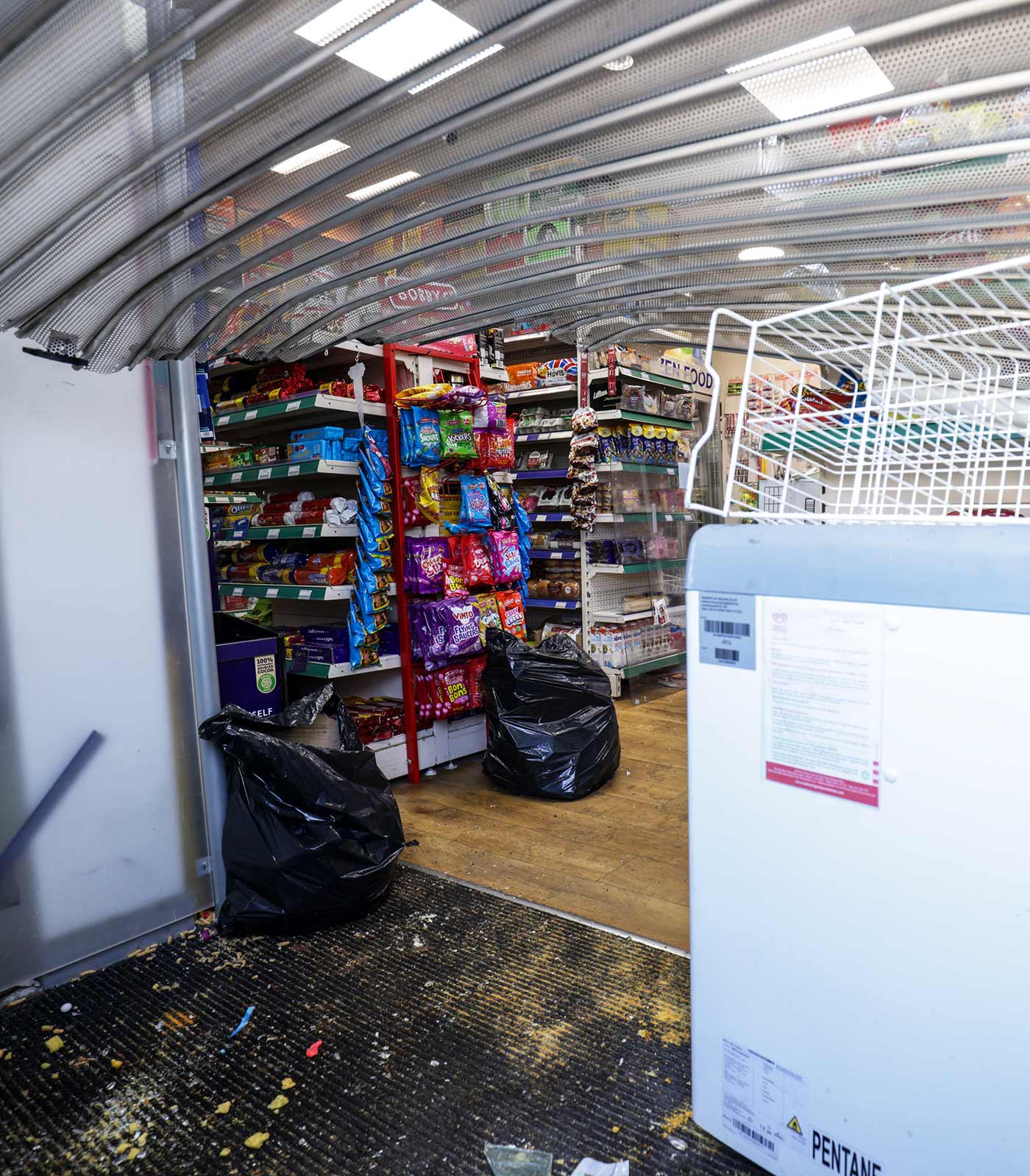 A view inside the Windsor Mini Mart, showing a broken shutter - 31 July 2024