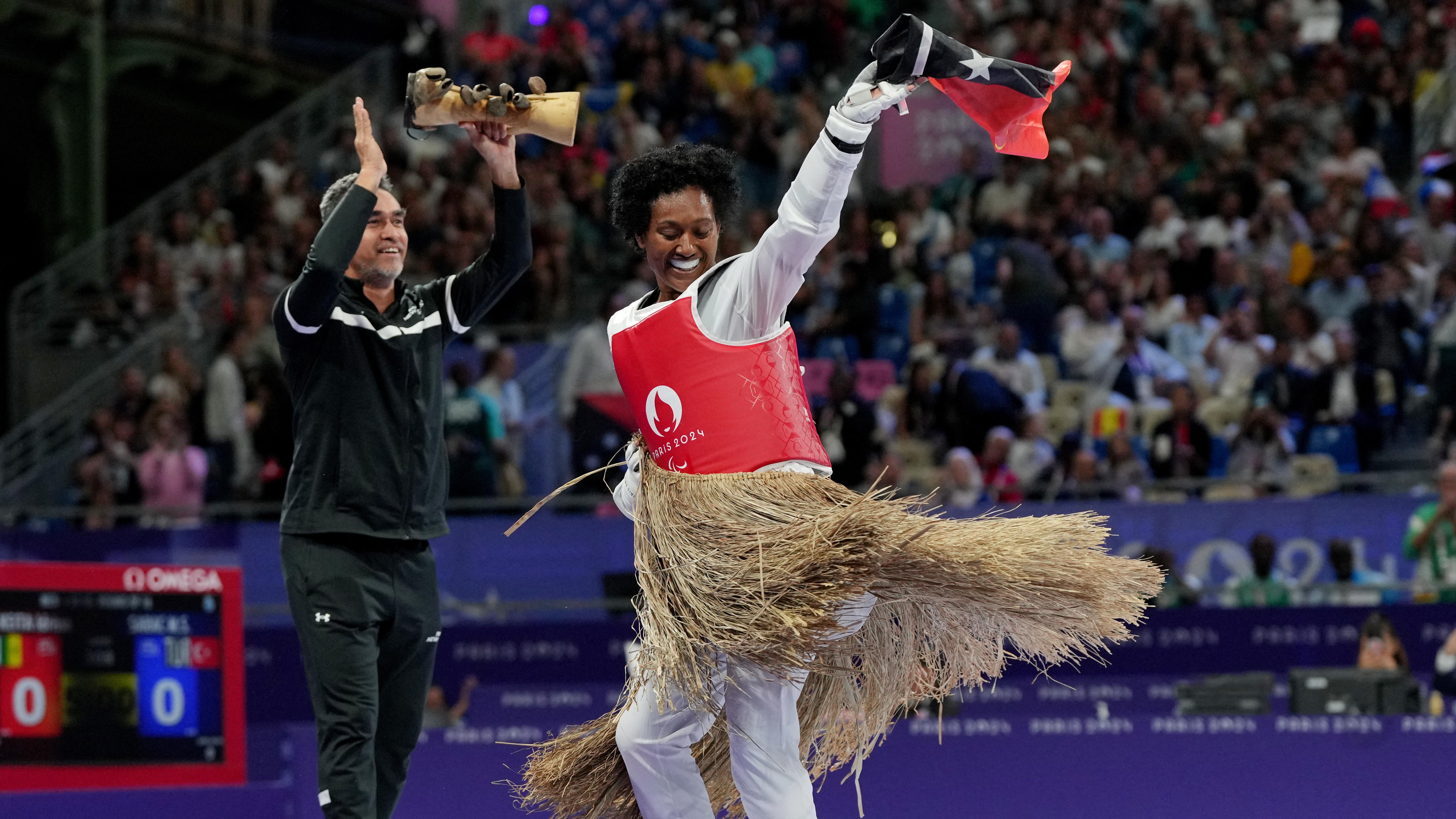 Manega Tapari dances while her trainer plays an instrument after losing a competition in taekwondo