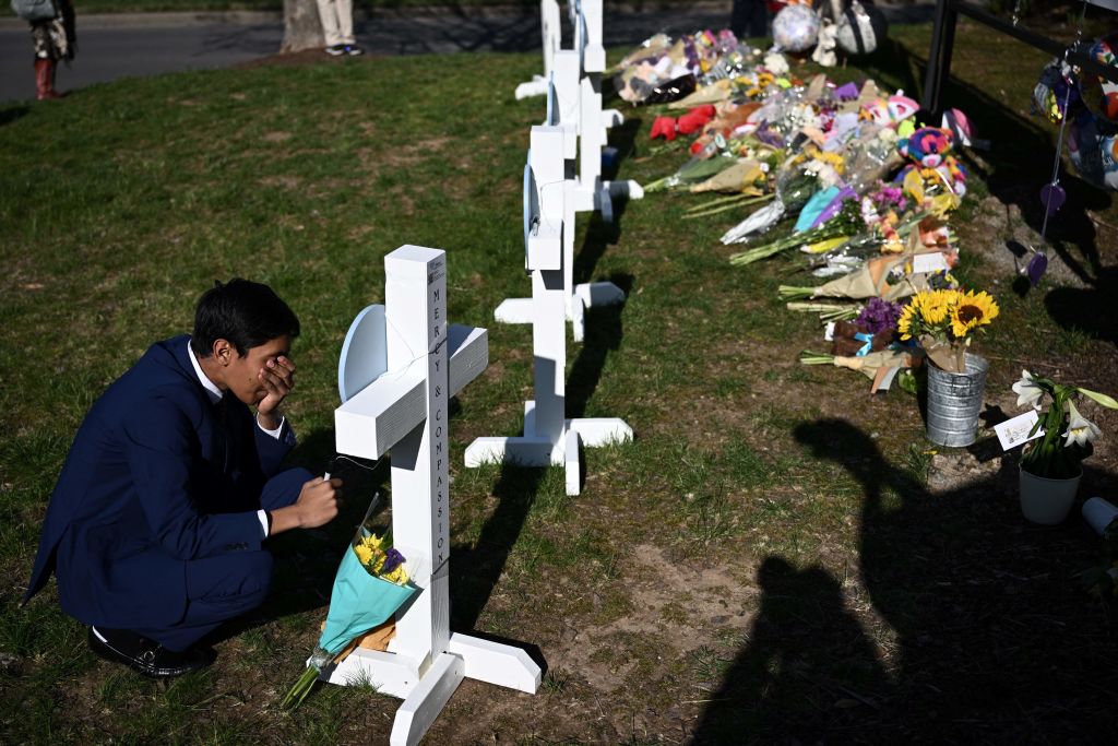 Alexander Reddy, who's friend's little sister is Hallie Scruggs, pays respects at a makeshift memorial for victims by the Covenant School building in Nashville, Tennessee, March 28, 2023.