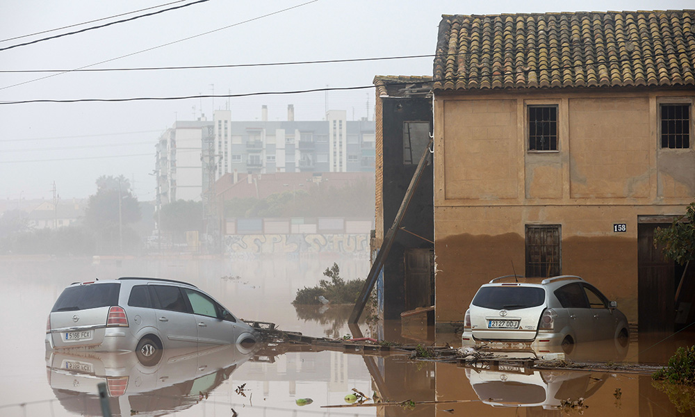 Two cars are partially submerged in the flooded streets of Sedaví