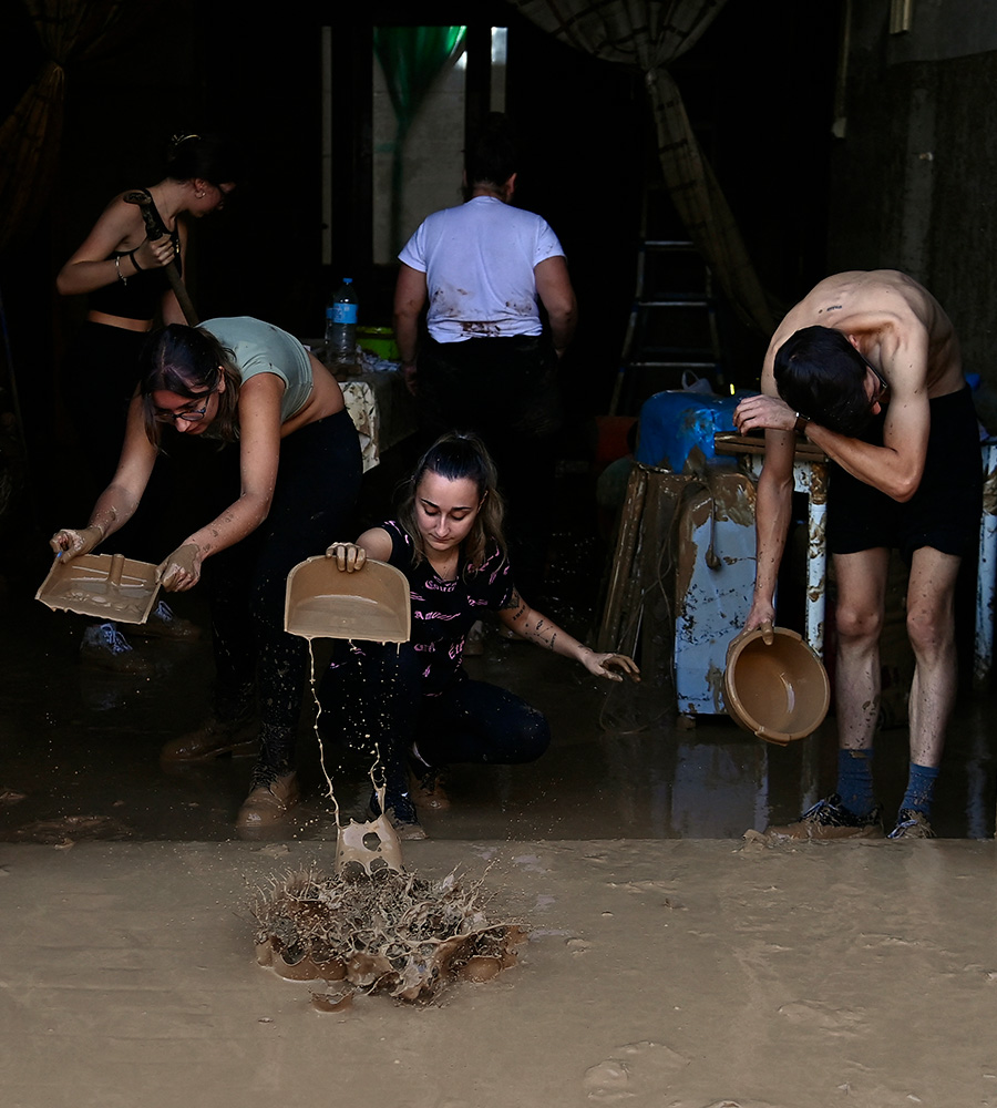 Family clears debris from their home, scooping out muddy water