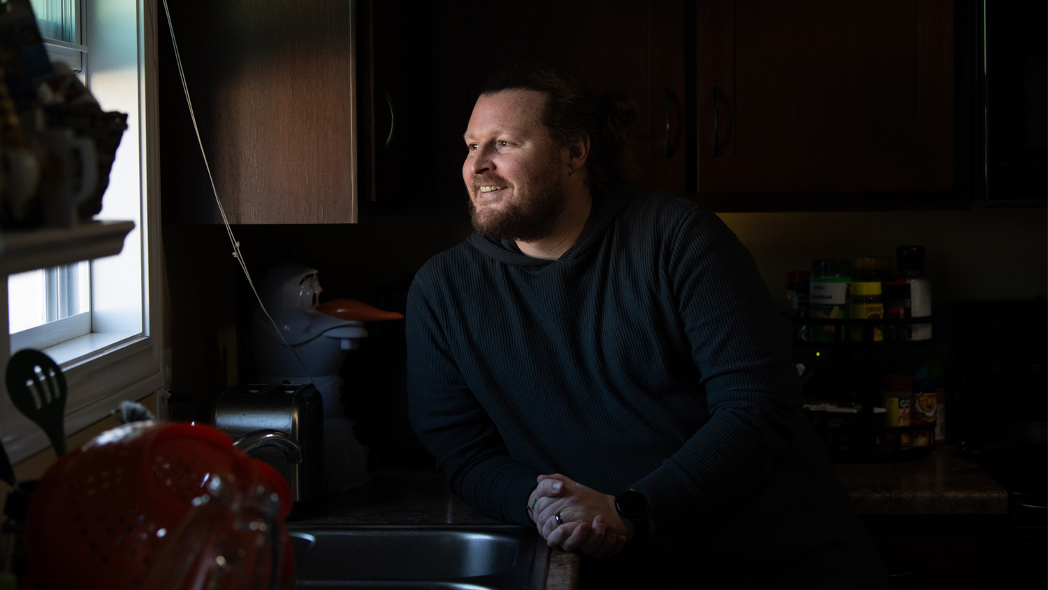 John Doty smiles as he looks through his kitchen window.