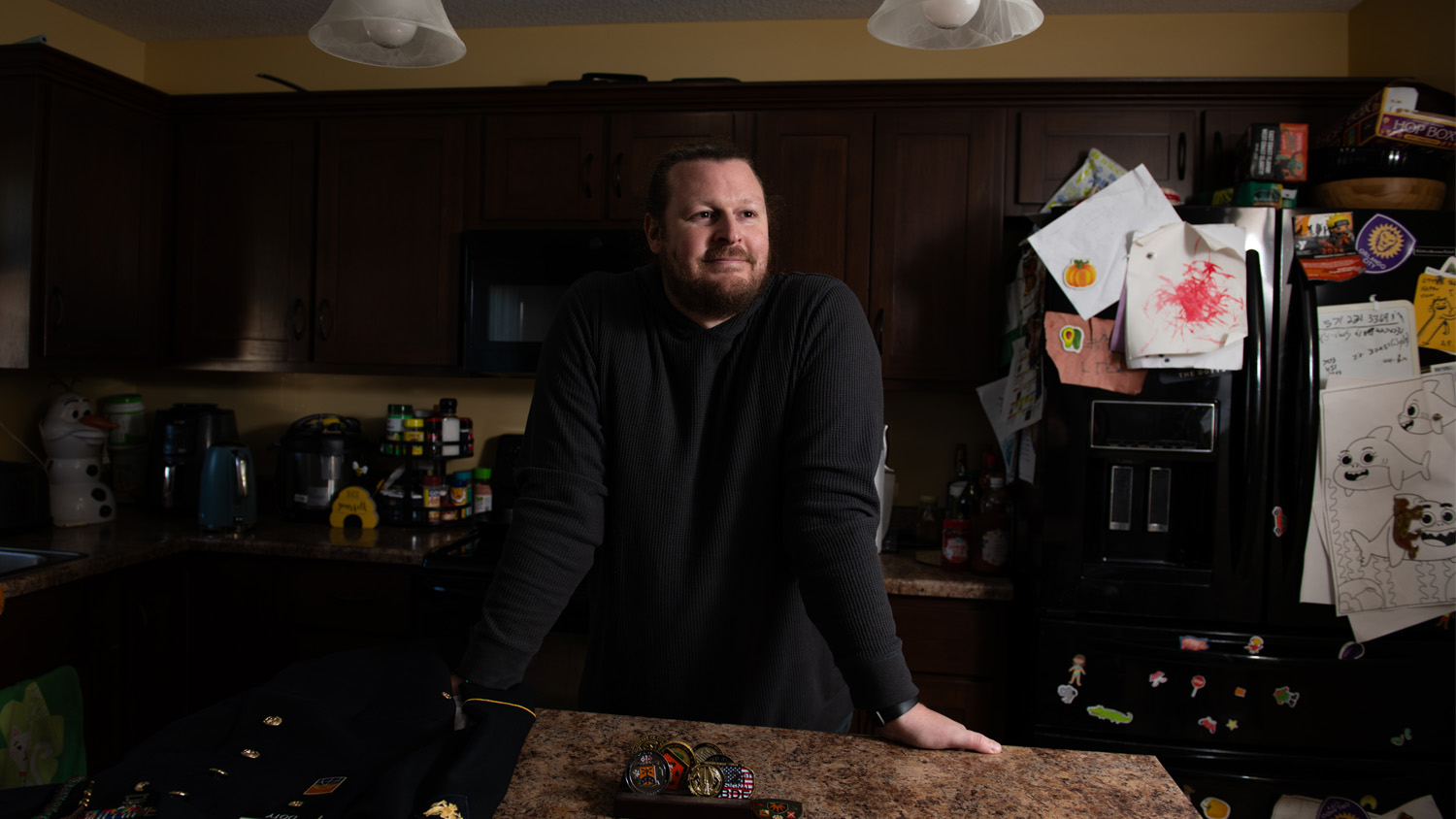 John Doty smiles as he leans over a dining table in front of his kitchen.