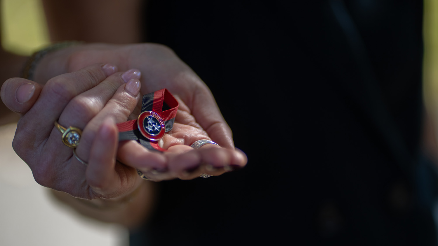 Melissa Alexander and Mary Joyce jointly hold a pin given out at the funeral of Katherine Koonce, the headmaster of Covenant School who was killed in a shooting.