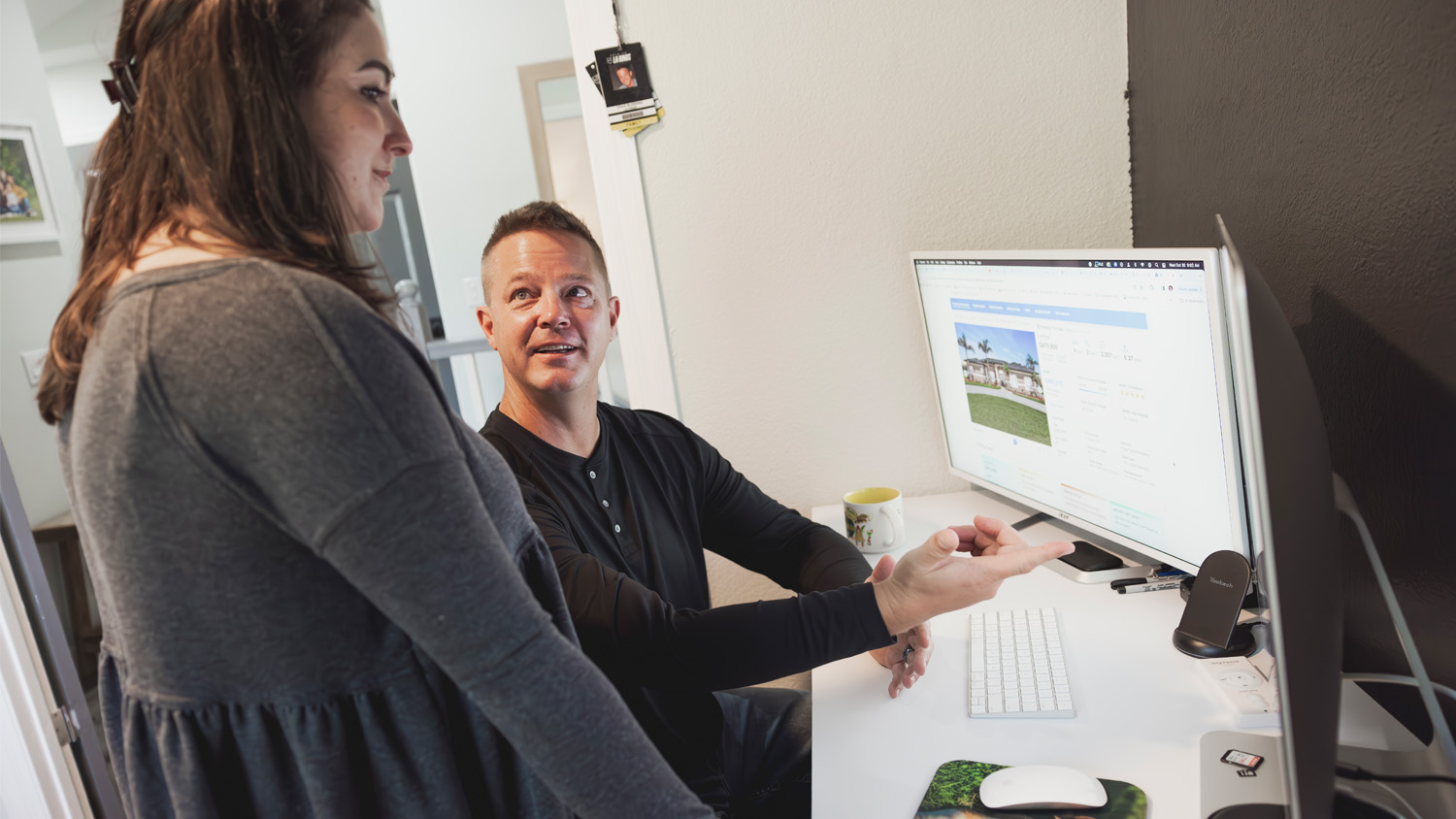 Craig and Brianna talk while looking at houses for rent and sale in a computer in their house