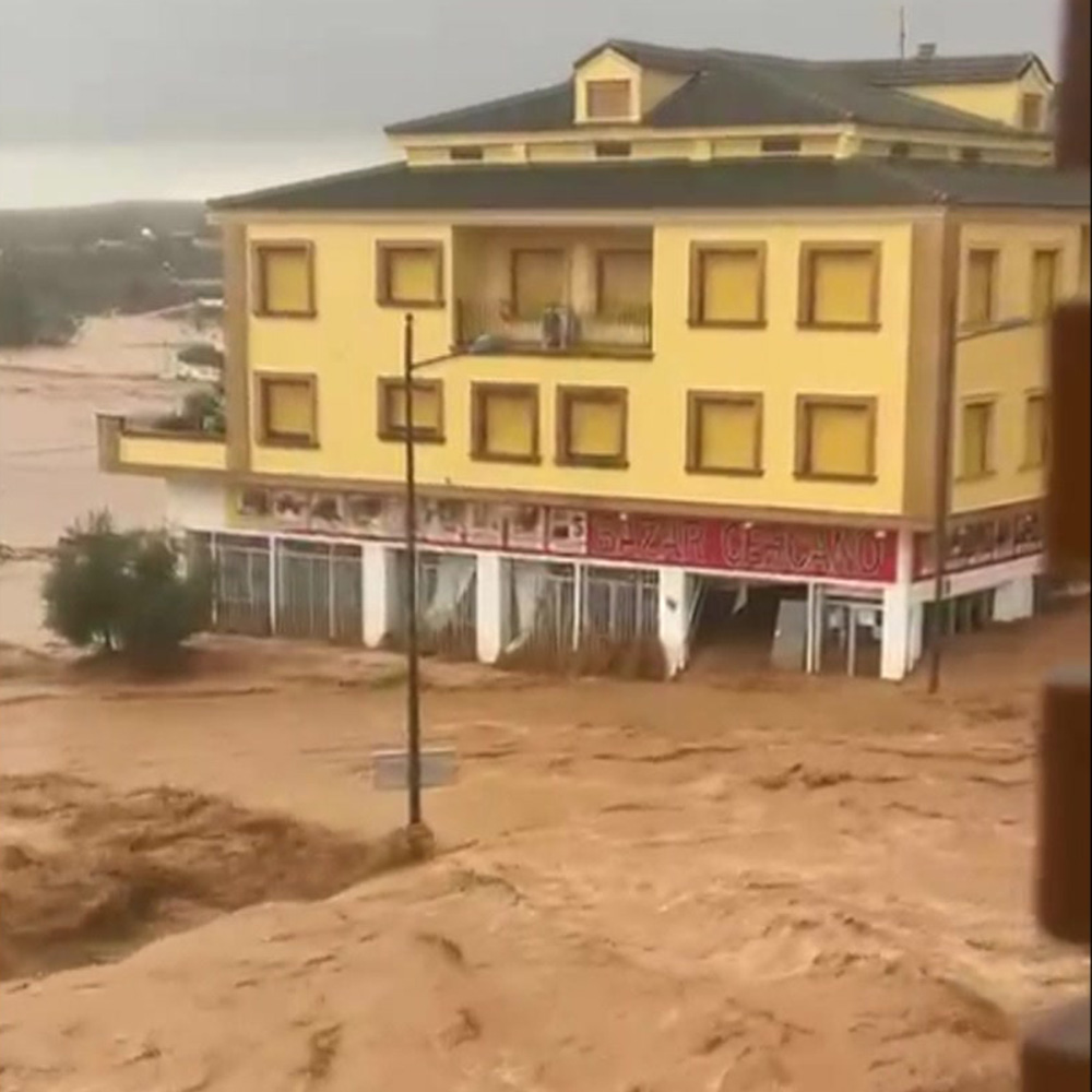 Floodwaters flow around a large building