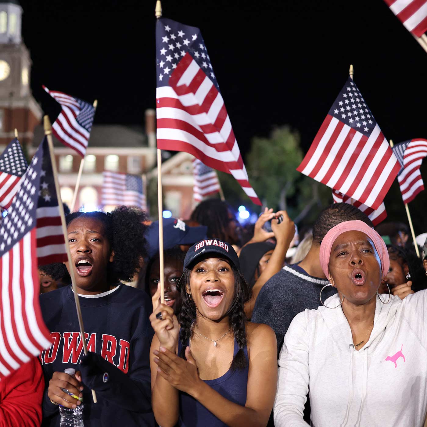 Kamala Harris supporters wave US flags at an election night event in Washington DC (Charly Triballeau/AFP)