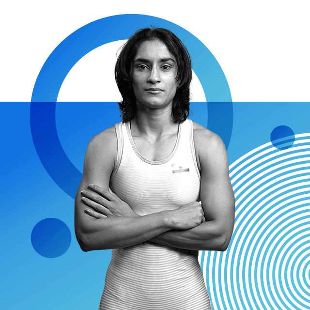 Wrestler Vinesh Phogat, with her hair cut just above her shoulders and arms crossed over her chest and wearing wrestling singlets with a small Indian flag logo printed on the left of the chest. She is looking directly at the camera.