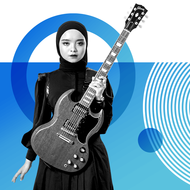 Hijab-wearing musician Firda Marsya Kurnia with a nose piercing and wearing a black dress with leather detail, holding an electric guitar with her left hand in front of her.