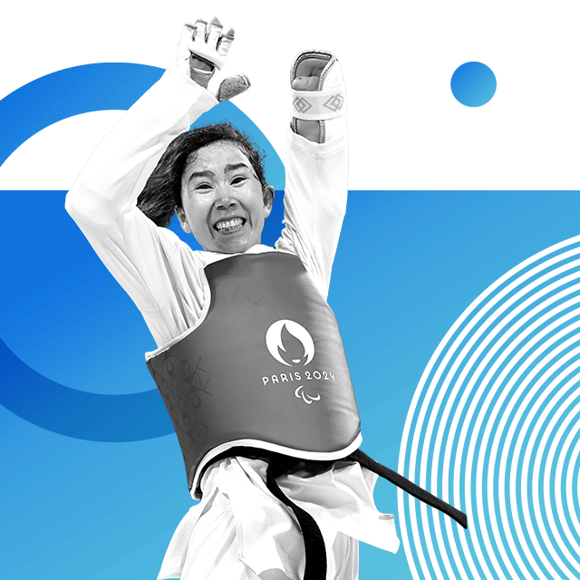 Paralympian Zakia Khudadadi, who was born without her left forearm, jumping in a white taekwondo tracksuit with a belt and a vest that reads Paris 2024.