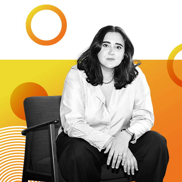 Fem-tech entrepreneur Nour Emam is sitting on a chair bent slightly forward towards the camera, with her hands resting on her knees. She has dark shoulder-length hair and is wearing a necklace and pale shirt.