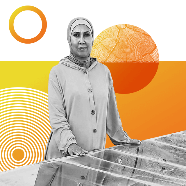 Engineer Enas Al-Ghoul poses next to a solar-powered panel, wearing a headscarf and a traditional long buttoned coat.