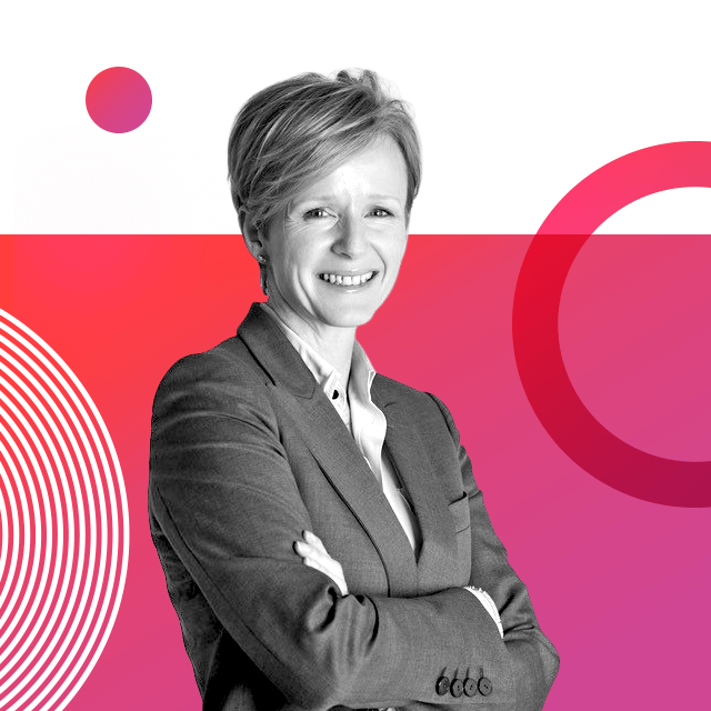 Co-founder of Monumental Welsh Women Helen Molyneux, with short light hair, is wearing a suit blazer with her arms folded and smiling into the camera.