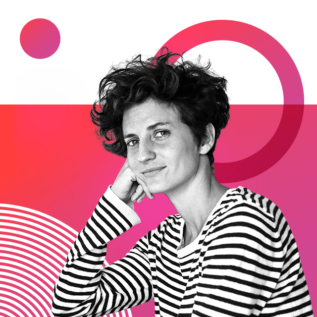 Graphic designer Idania Del Río has short thick hair and is sitting with one hand resting on the side of her face. She is wearing a black and white horizontal striped top.