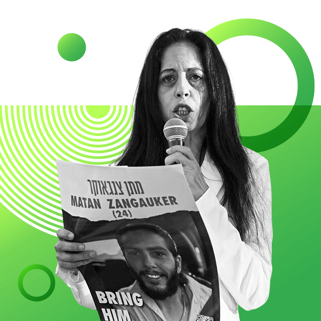 Mother and campaigner Einav Zangauker pictured with long hair and a white collared shirt on, speaking into a hand microphone as she holds a poster with a picture of her son and hostage, 24-year-old Matan Zangauker.