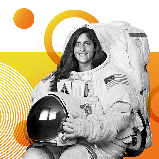 Astronaut Sunita Williams wearing a full Nasa space suit with the American flag on its arm, clutching her space helmet and smiling at the camera.