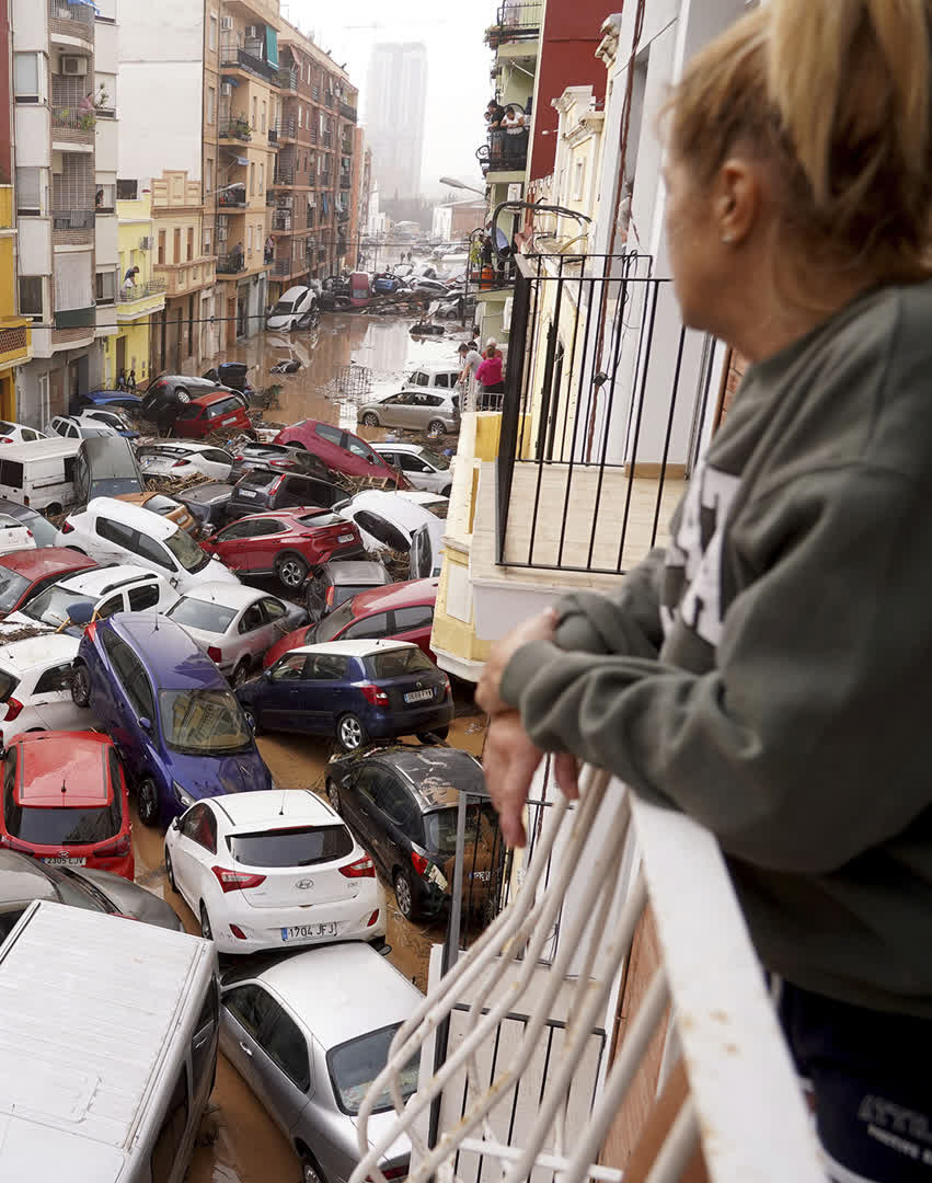 A woman looks out from her balcony as vehicles are trapped in the street during flooding in Valencia, Wednesday, Oct. 30, 2024.