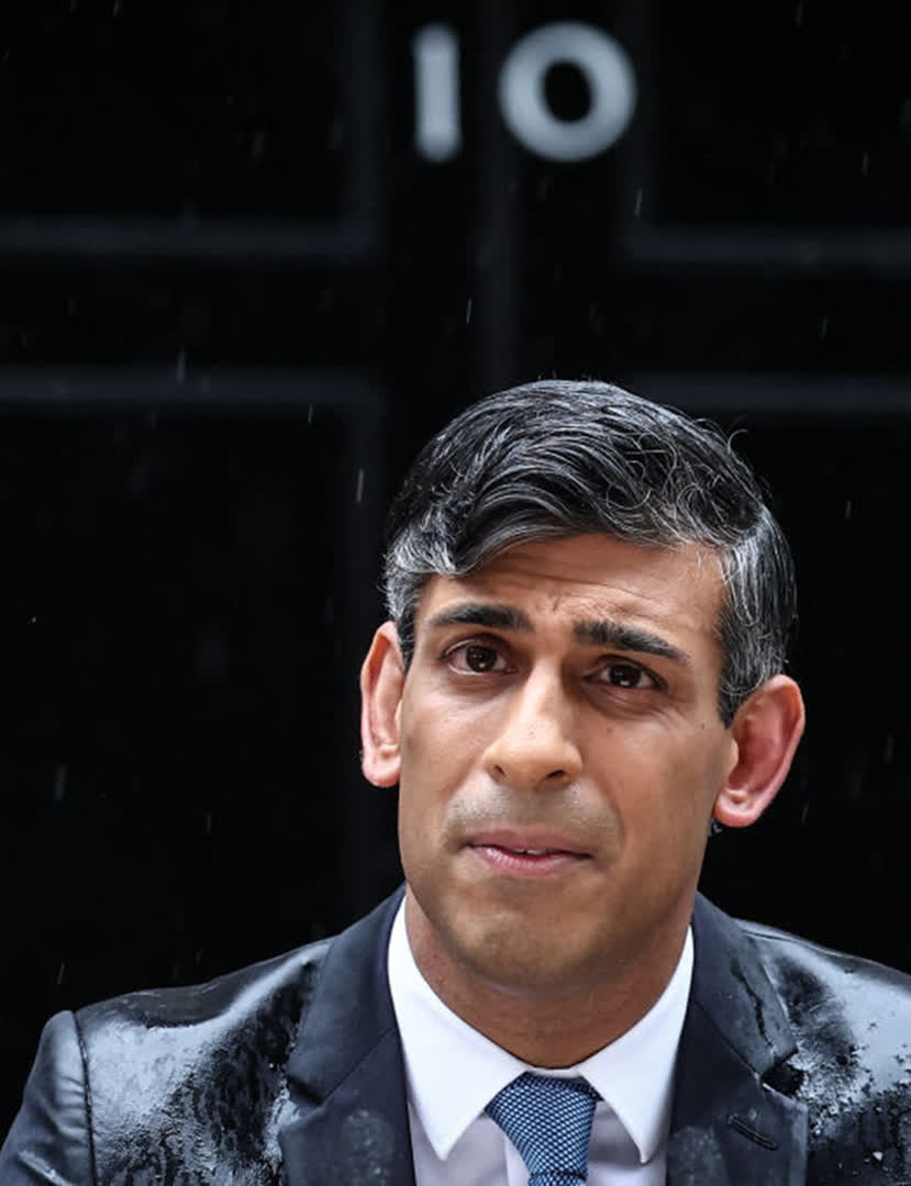 Britain's Prime Minister Rishi Sunak, soaked in rain, pauses as he delivers a speech to announce July 4 as the date of the UK's next general election, at 10 Downing Street in central London, on May 22, 2024. 