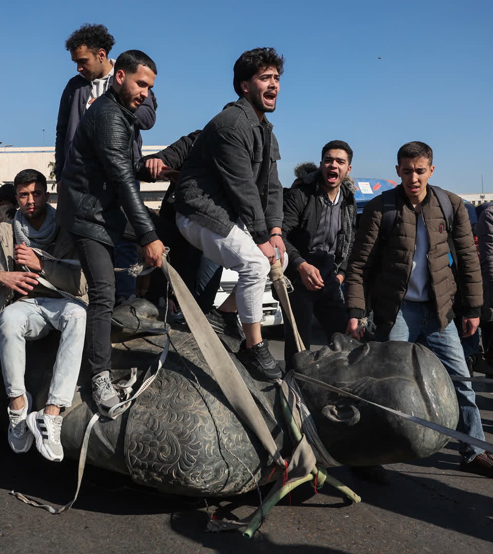 Students drag a toppled statue of late president Hafez al-Assad on the street during a rally near the campus of the Damascus University in the Syrian capital on December 15, 2024. 