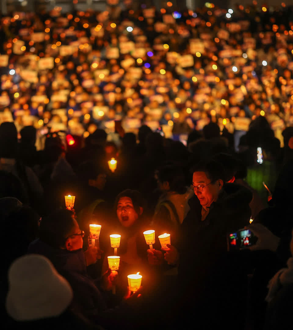 People hold candles and signs during a candlelight vigil to demand the resignation of South Korean President Yoon Suk Yeol, who declared martial law which was reversed hours later, at the National Assembly in Seoul, South Korea, December 5, 2024.