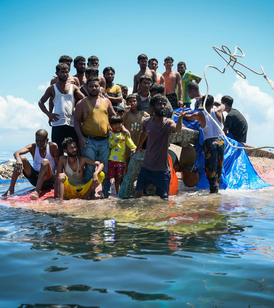 Rohingya refugees stand on their capsized boat, 21 March 2024.