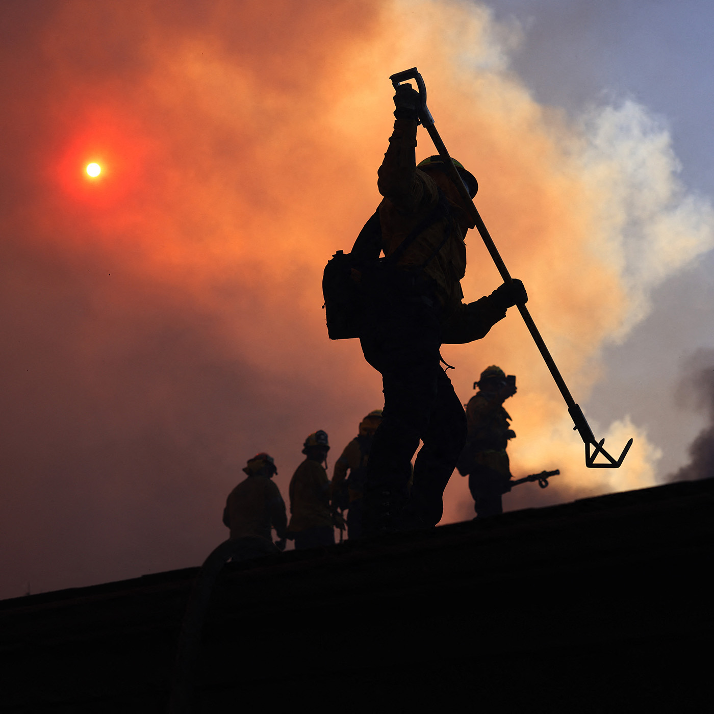 Firefighters work as a brush fire burns in Pacific Palisades